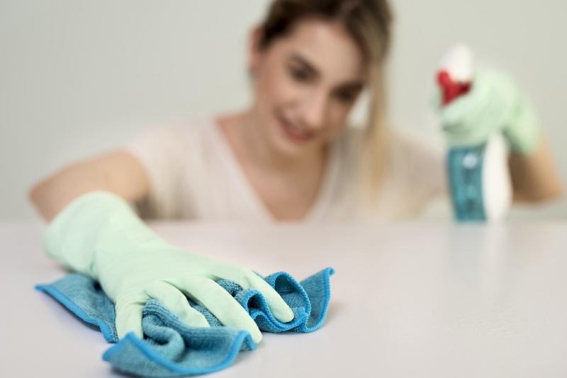 The girl with gloves and spray is cleaning