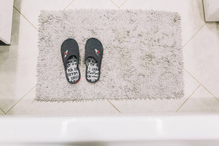 A clean bathroom mat with slippers on it.